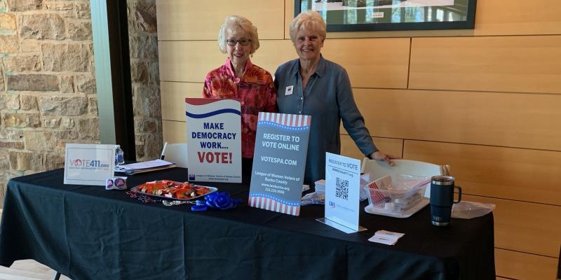 2 women stand in front of voter registration table