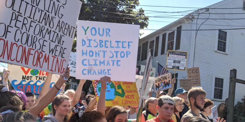 Students at the Dennis Glbal Climate March. sign reads "Your disbelief won't stop climate change".