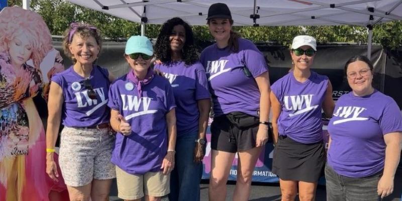Six women in purple shirts, standing, smiling at camera