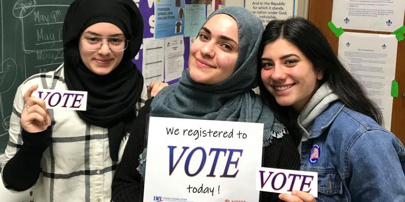 High school students pose with "WE REGISTERED TO VOTE TODAY" and "VOTE" signs