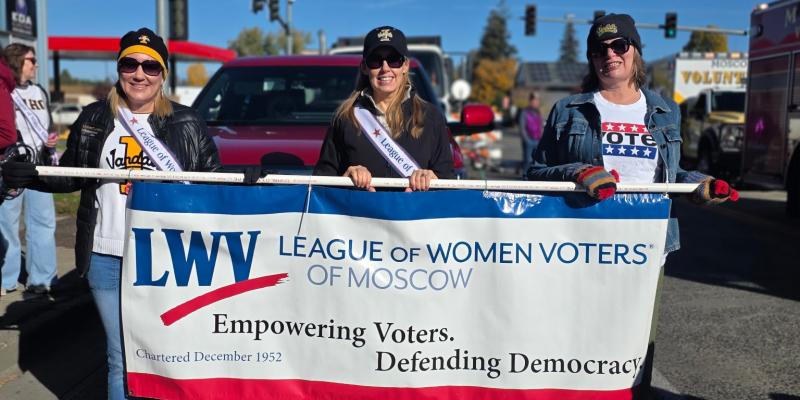 Three women holding a League of Women Voters of Moscow banner