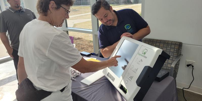 A volunteer is shown how a Pulaski County voting machine works.