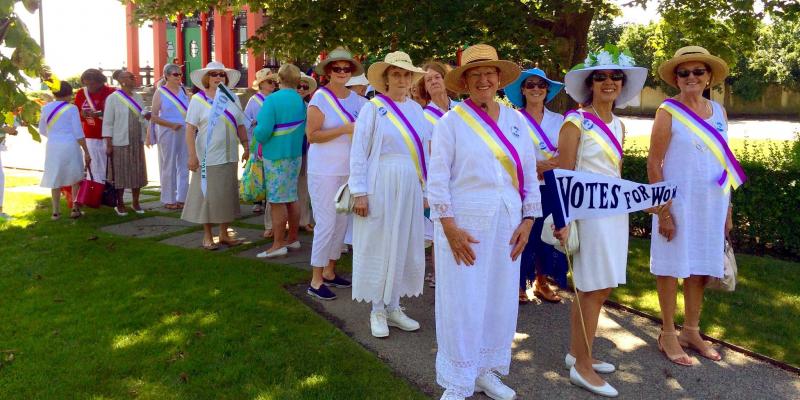 LWVRI members dressed as suffragettes, holding VOTES FOR WOMEN signs
