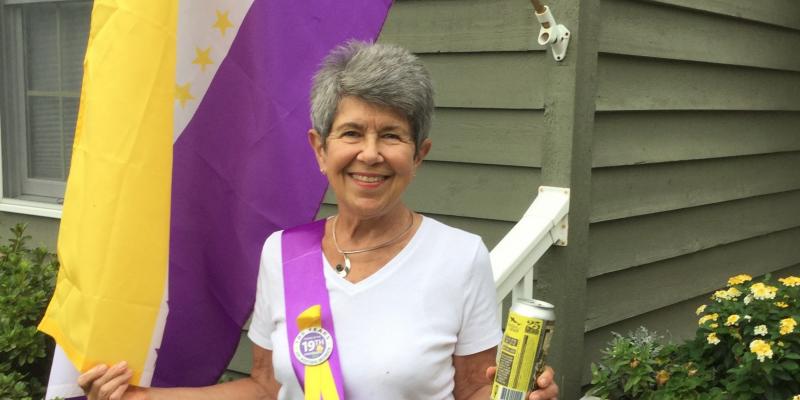 Sue Claire Harper flies 19th Amendment flag while holding a can of Centennial Suds
