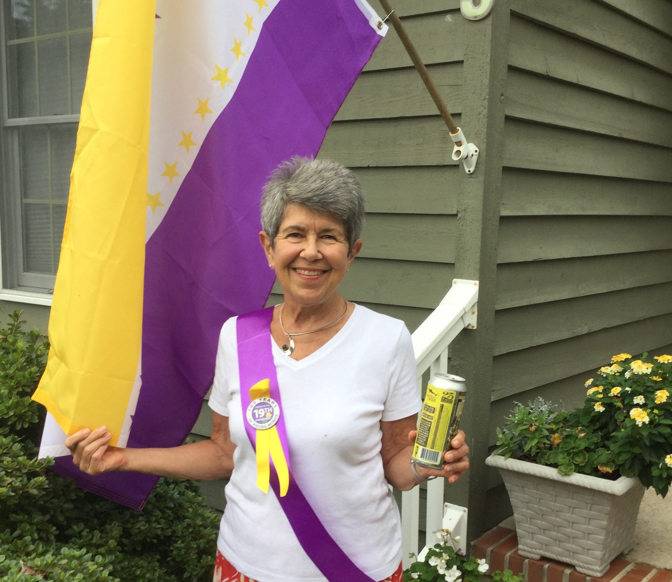 Sue Claire Harper flies 19th Amendment flag while holding a can of Centennial Suds