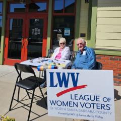 NatVoterRegDay-shows woman & man at LWV tabling outside library